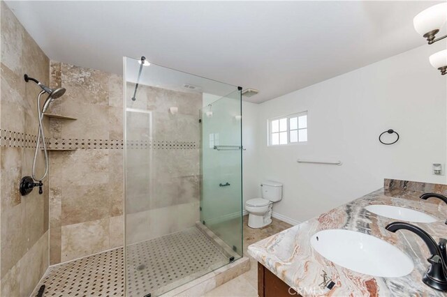 bathroom featuring a shower with door, vanity, and toilet