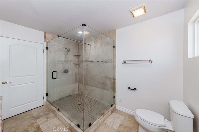 bathroom featuring a shower with door and toilet