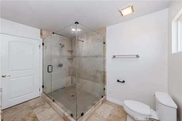 bathroom with a stall shower, baseboards, and toilet