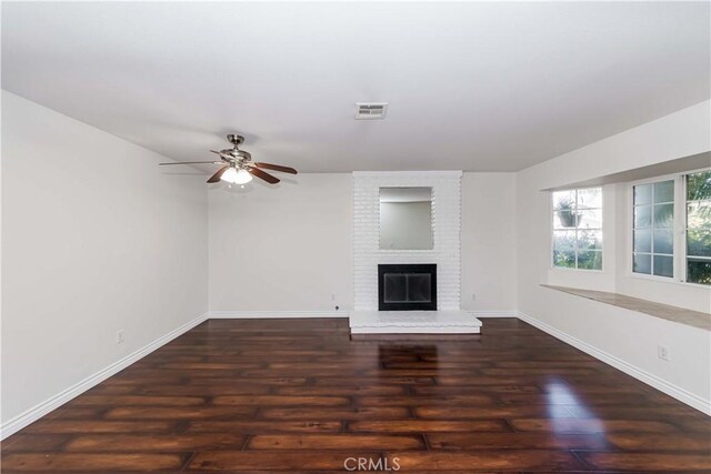 unfurnished living room with ceiling fan, dark hardwood / wood-style floors, and a brick fireplace