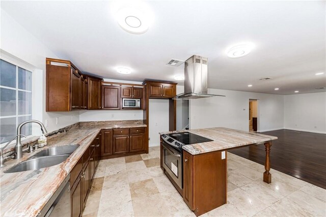 kitchen with sink, appliances with stainless steel finishes, a center island, light stone counters, and island range hood