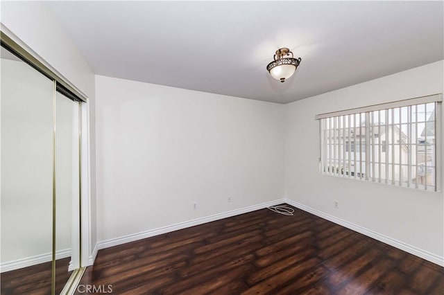 unfurnished bedroom featuring dark wood-type flooring and a closet