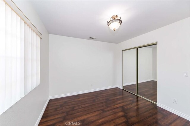 unfurnished bedroom with dark hardwood / wood-style floors and a closet