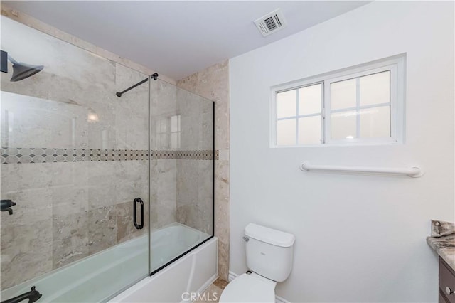 bathroom featuring toilet, bath / shower combo with glass door, vanity, and visible vents