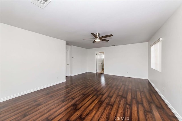 spare room featuring baseboards, visible vents, ceiling fan, and dark wood-type flooring