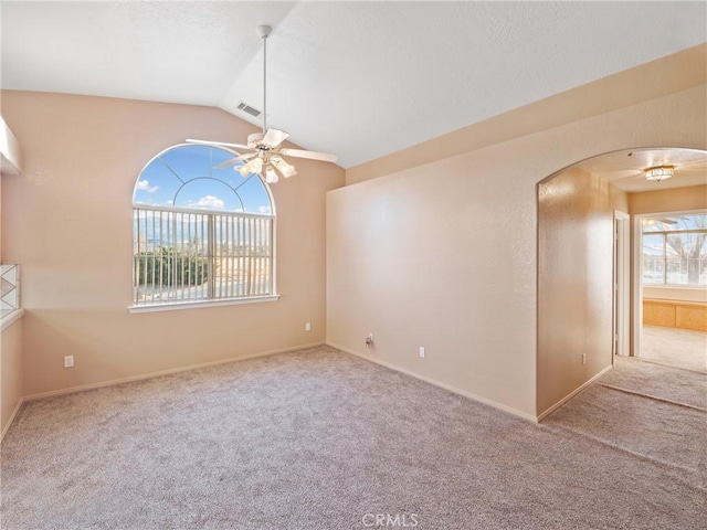 empty room featuring ceiling fan, a healthy amount of sunlight, carpet flooring, and vaulted ceiling