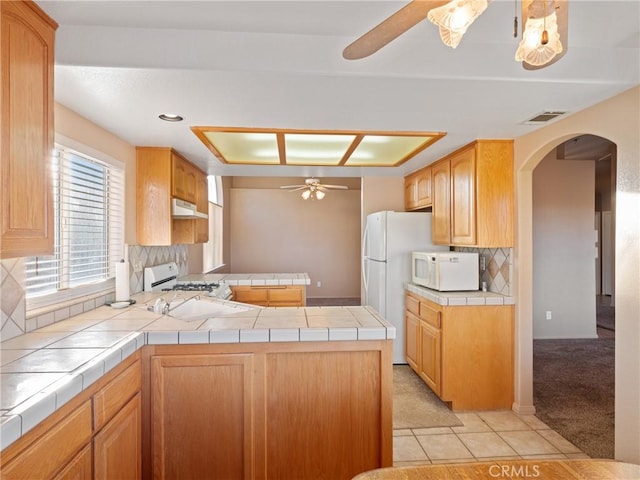 kitchen featuring ceiling fan, white appliances, tile countertops, and backsplash