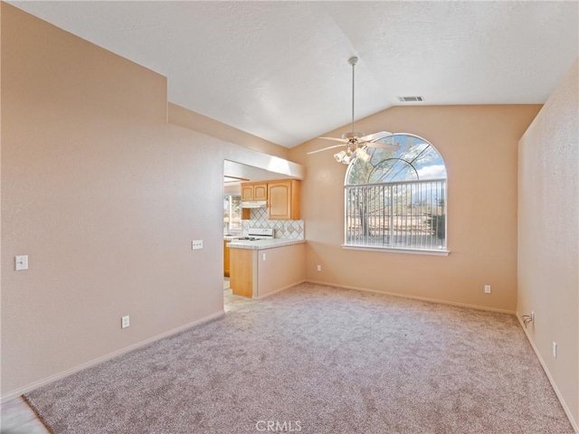 unfurnished living room with lofted ceiling, light carpet, and ceiling fan