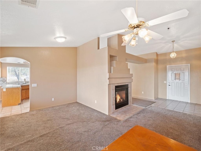 unfurnished living room with vaulted ceiling, a fireplace, sink, ceiling fan, and light carpet