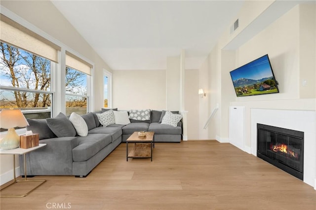 living room featuring lofted ceiling and light hardwood / wood-style flooring