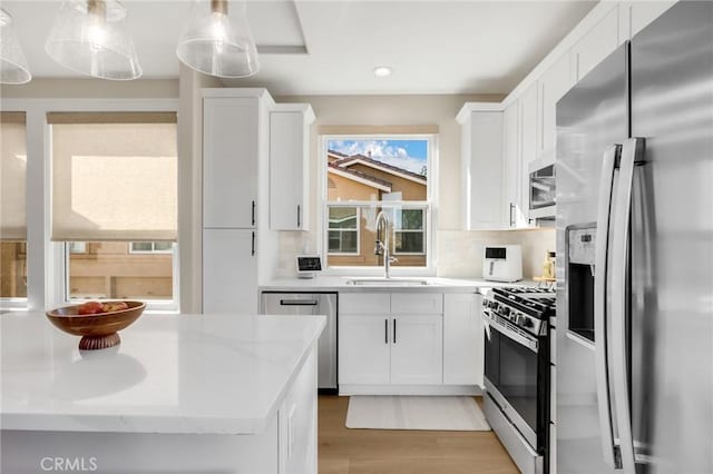 kitchen featuring stainless steel appliances, white cabinetry, tasteful backsplash, and pendant lighting