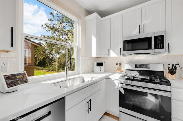 kitchen featuring light stone counters, appliances with stainless steel finishes, sink, and white cabinets