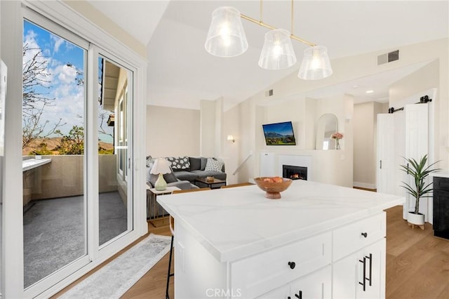 kitchen with a breakfast bar, white cabinetry, a center island, decorative light fixtures, and vaulted ceiling