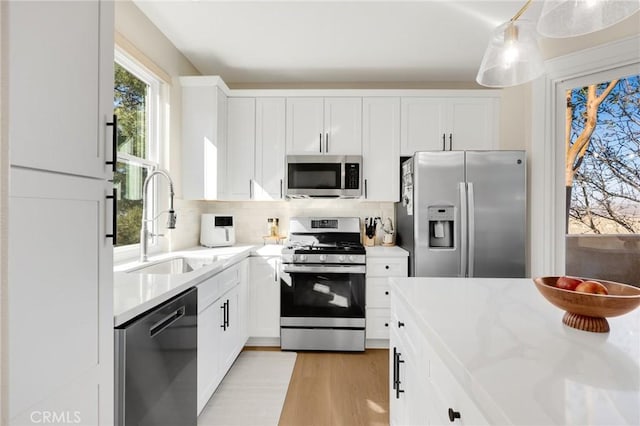 kitchen featuring sink, white cabinetry, tasteful backsplash, decorative light fixtures, and stainless steel appliances