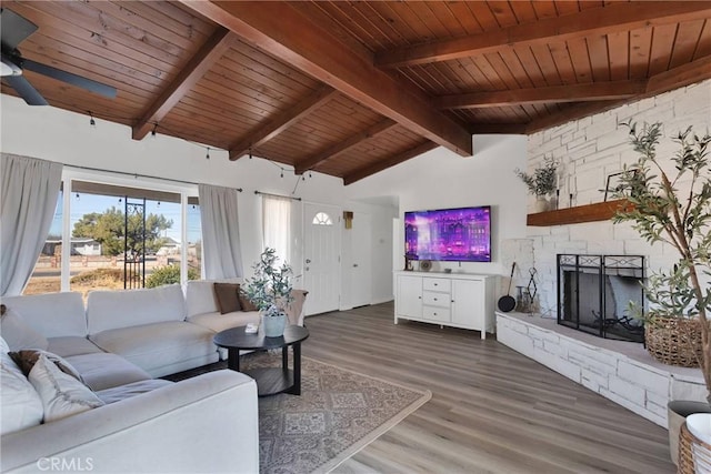 living room with a fireplace, wood-type flooring, vaulted ceiling with beams, ceiling fan, and wood ceiling