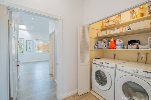 clothes washing area featuring washing machine and dryer and light hardwood / wood-style floors