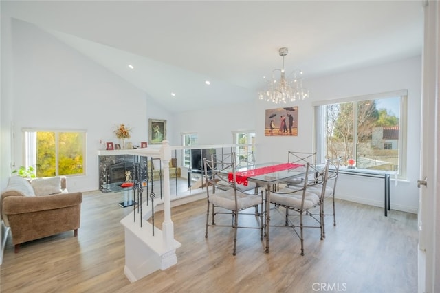 dining space featuring an inviting chandelier, a high end fireplace, high vaulted ceiling, and light wood-type flooring