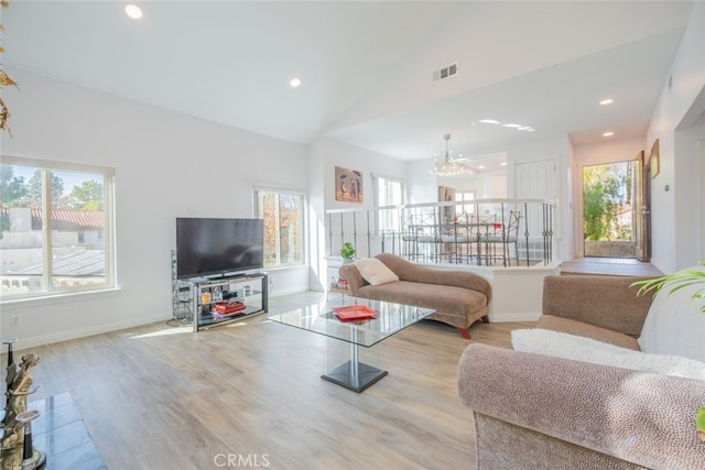 living room with light hardwood / wood-style flooring, high vaulted ceiling, and a chandelier