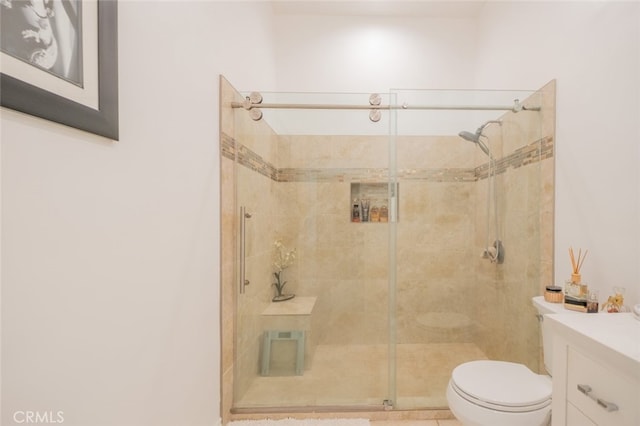 bathroom featuring vanity, a shower with shower door, and toilet