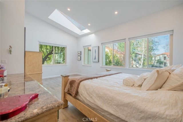 bedroom featuring lofted ceiling with skylight and light hardwood / wood-style floors