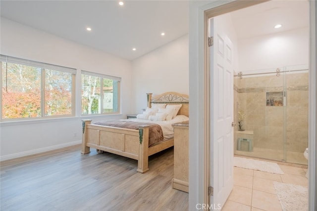 bedroom with vaulted ceiling, ensuite bath, and light hardwood / wood-style flooring