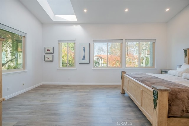 bedroom with light hardwood / wood-style floors and a skylight