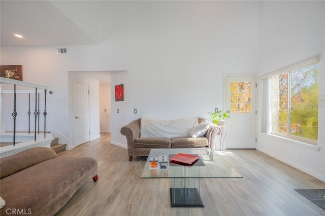 living room with a towering ceiling and light hardwood / wood-style flooring