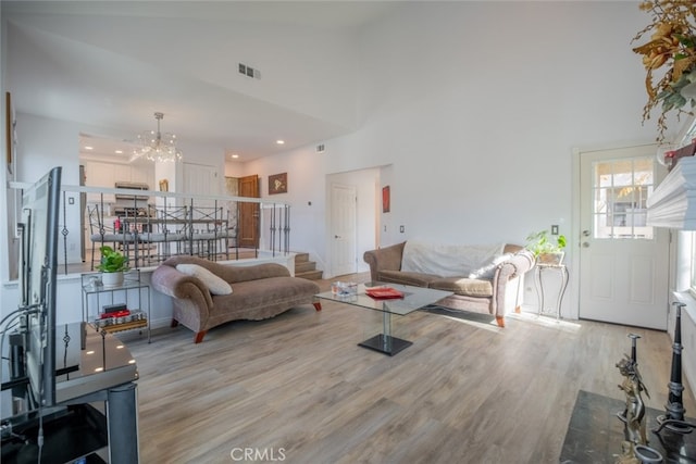 living room with a high ceiling, a notable chandelier, and light hardwood / wood-style floors