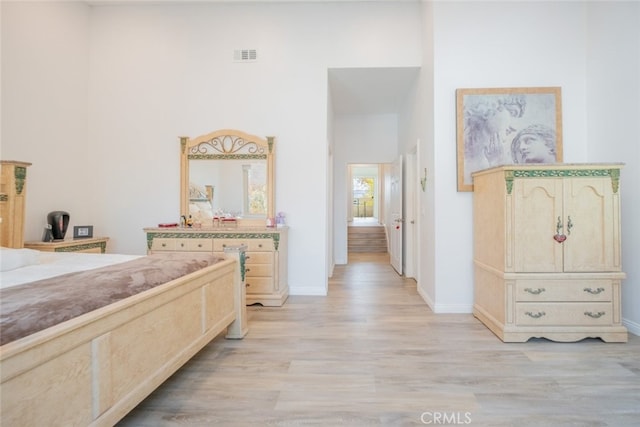 bedroom with light hardwood / wood-style flooring and a high ceiling