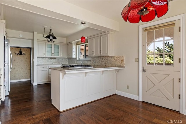 kitchen with a kitchen bar, tasteful backsplash, dark hardwood / wood-style flooring, kitchen peninsula, and white cabinets