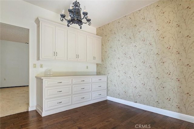 spare room with an inviting chandelier and dark hardwood / wood-style flooring