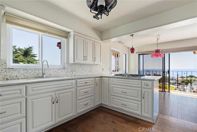 kitchen featuring decorative light fixtures, white cabinetry, sink, stainless steel gas cooktop, and kitchen peninsula