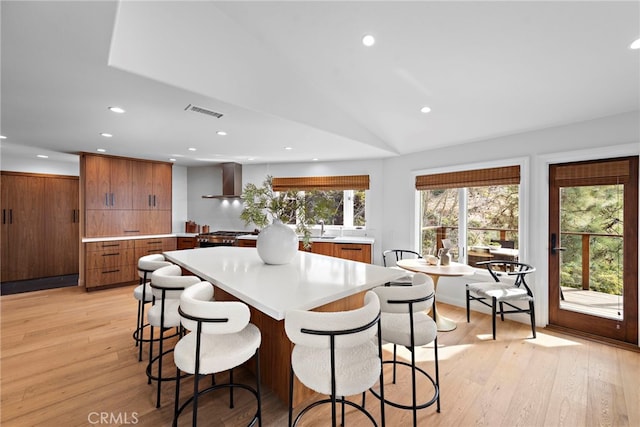 2335 Hillview Dr, Laguna Beach, CA 92651 - kitchen featuring wall chimney range hood, light countertops, light wood-style flooring, recessed lighting, and a kitchen bar
