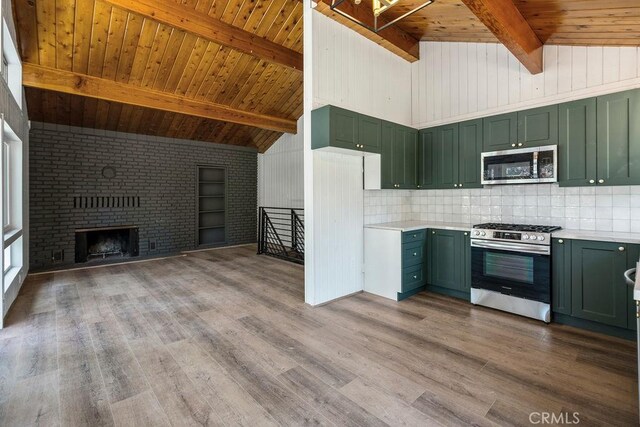 kitchen featuring brick wall, hardwood / wood-style floors, beamed ceiling, green cabinets, and stainless steel appliances