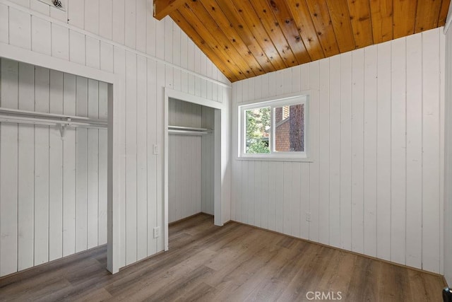 unfurnished bedroom featuring hardwood / wood-style flooring, vaulted ceiling with beams, wooden walls, wooden ceiling, and a closet