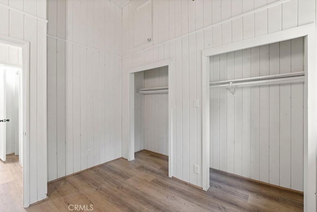 unfurnished bedroom featuring hardwood / wood-style floors, wood walls, and a closet