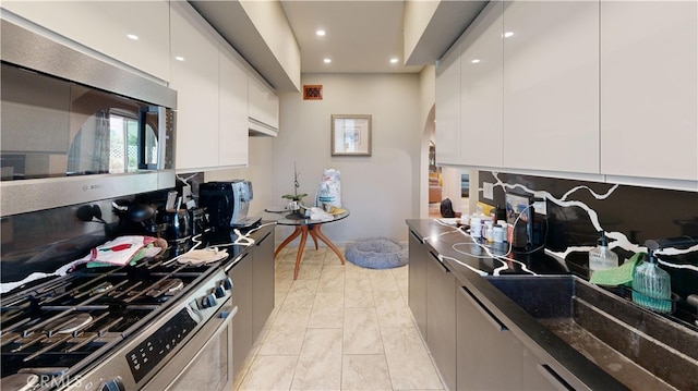 kitchen with white cabinetry, tasteful backsplash, dark stone countertops, and appliances with stainless steel finishes