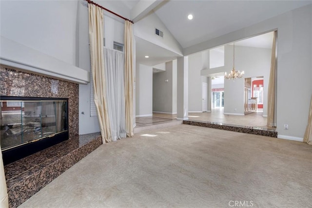 carpeted living room with an inviting chandelier, a high end fireplace, and high vaulted ceiling