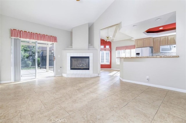 unfurnished living room featuring ceiling fan, lofted ceiling, plenty of natural light, and a fireplace