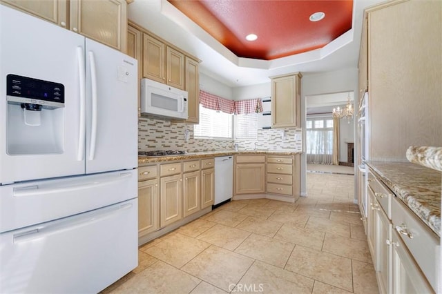 kitchen with white appliances, a healthy amount of sunlight, a tray ceiling, and light brown cabinets