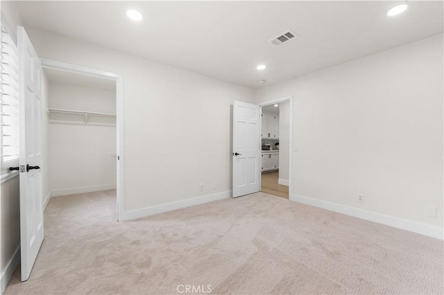 unfurnished bedroom featuring light colored carpet and a closet