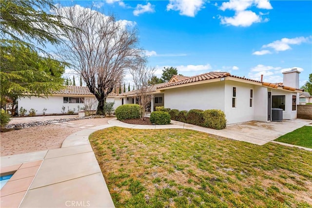 view of front of property with central AC, a front lawn, and a patio area