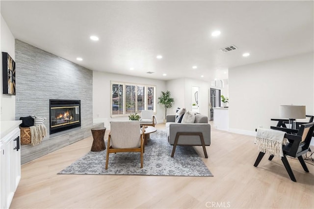 living room featuring a tiled fireplace and light hardwood / wood-style floors