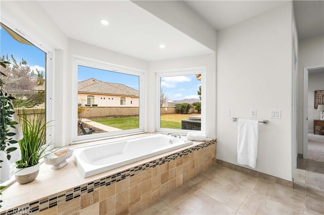 bathroom with a relaxing tiled tub and tile patterned flooring