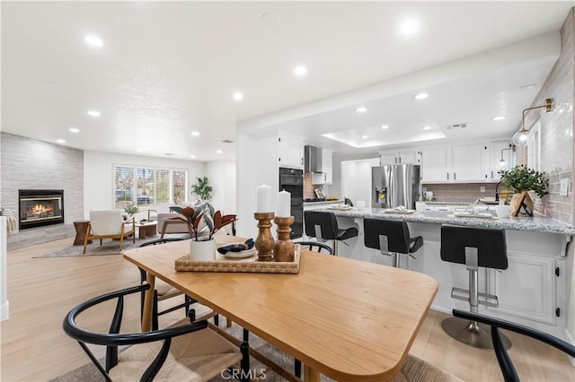 dining area with a tray ceiling, a fireplace, and light hardwood / wood-style floors