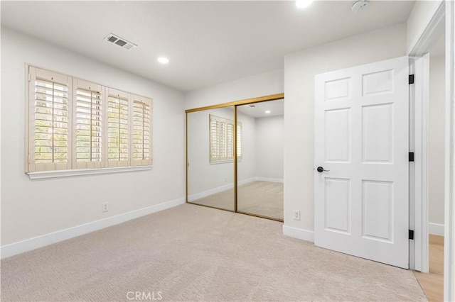 unfurnished bedroom featuring light carpet and a closet