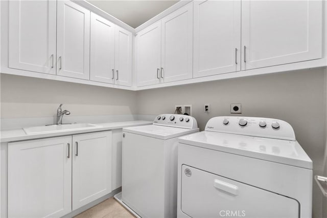 laundry room featuring sink, light tile patterned floors, washing machine and dryer, and cabinets