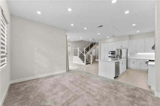 kitchen featuring extractor fan, sink, a center island with sink, stainless steel appliances, and white cabinets