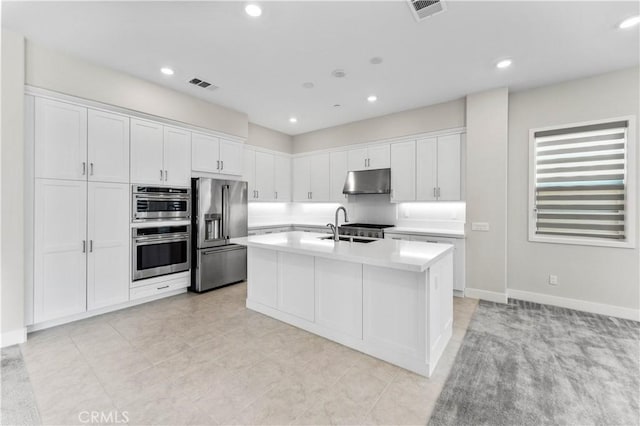 kitchen featuring light tile patterned flooring, appliances with stainless steel finishes, a center island with sink, and white cabinets