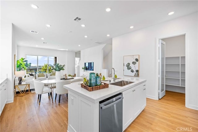 kitchen with sink, dishwasher, a kitchen island with sink, and white cabinets